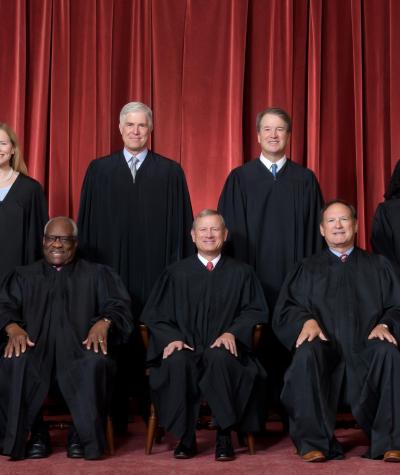 picture of nine justices sitting in front of red curtains
