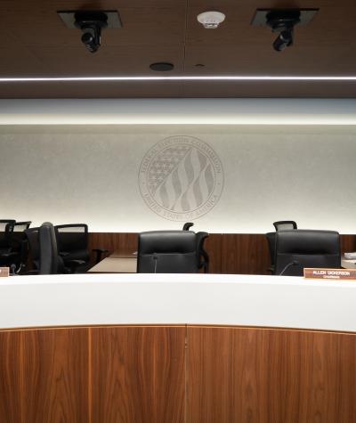 The logo of the FEC with several empty office chairs in front of it.