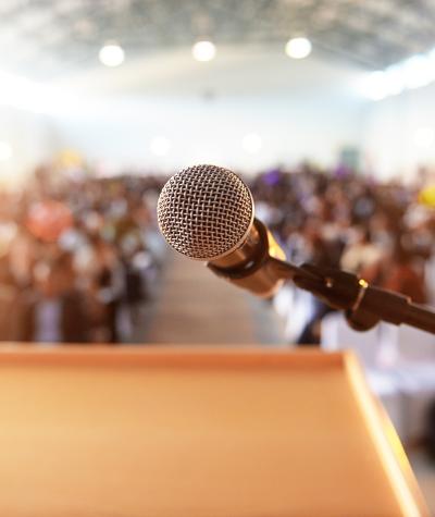 A microphone at a podium overlooking an audience out of focus in the background