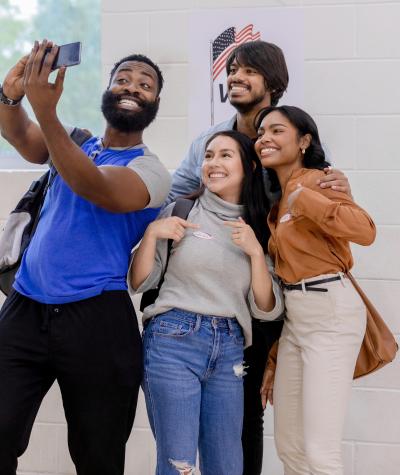 A group of diverse young Americans gather for a selfie photo after voting at their polling place