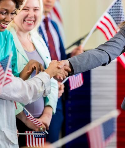 A woman shakes hands with a group of other women holding American flags