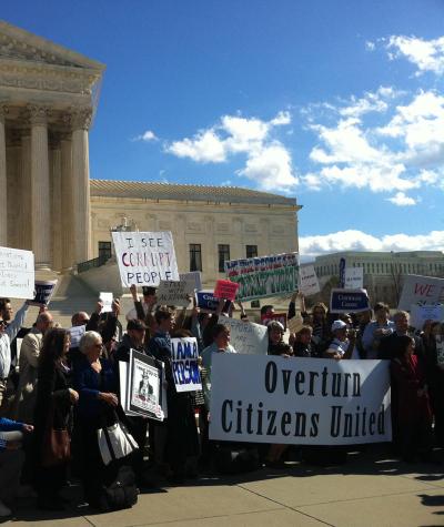 People gathered in front of the U.S. Supreme Court with signs saying "Overturn Citizens United"