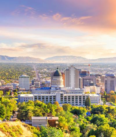 A view of the buildings in Salt Lake City with the mountains and sun behind them