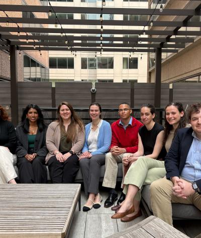 A group of people sitting on an outdoor couch on a roof deck