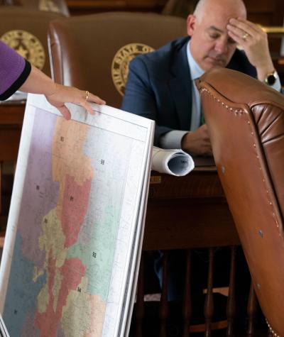 A woman sorts through a stack of large poster prints of maps