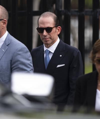 A man in a suit wearing sunglasses with other people around him also wearing sunglasses