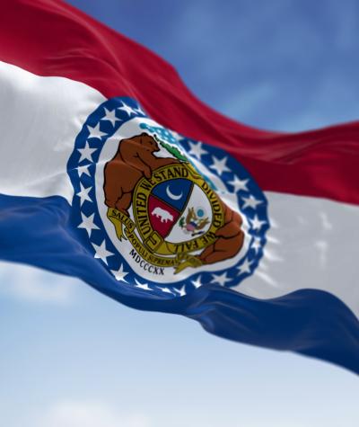 State flag of Missouri waving against a blue sky with white clouds