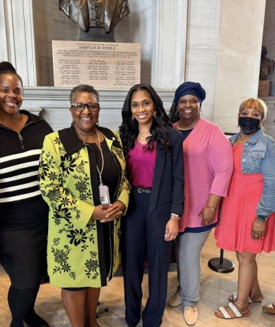 A group of seven people posing for a photo in a marble hallway.