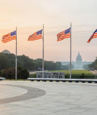 A shot from the Washington Monument frames the Capitol Building with American flags during sunset.