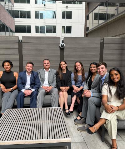 A group of people sitting on an outdoor couch on a roof deck.