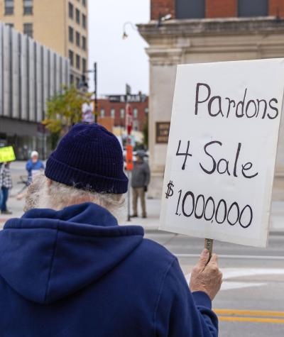 A man holds a sign that says "Pardons 4 Sale $1,000,000."