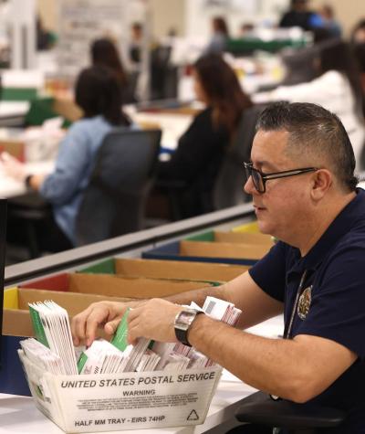 A man sorts through a box of ballots