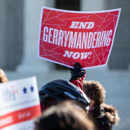 A concerned citizen holds a sign that says End Gerrymandering Now