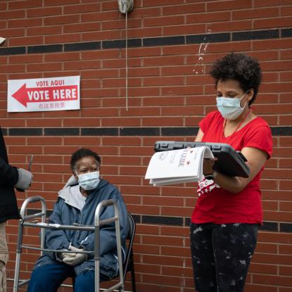 Voters and pollworkers wearing facemasks outside a polling place in DC