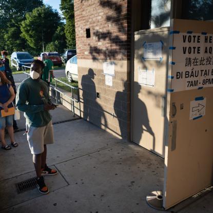 Voters wearing masks line up outside of a polling place in Boston, MA.