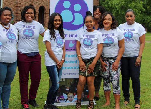 A group of women wearing Free Hearts t-shirts posing in front of a Free Hearts sign
