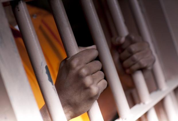 Stock photo of person behind prison bars