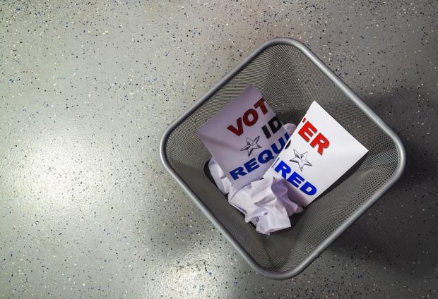 "Voter ID required" sign in a trash can