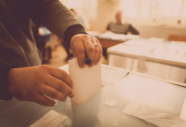 Voter placing ballot into box
