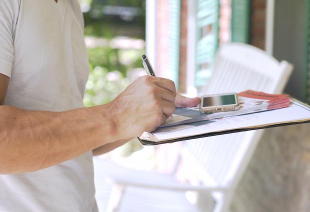 Person writing on clipboard