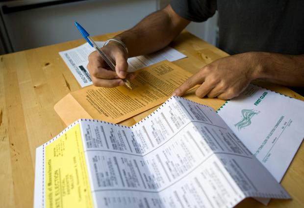 Shot of a person's hands at a table filling out an absentee ballot