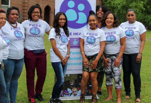 A group of women wearing Free Hearts t-shirts posing in front of a Free Hearts sign
