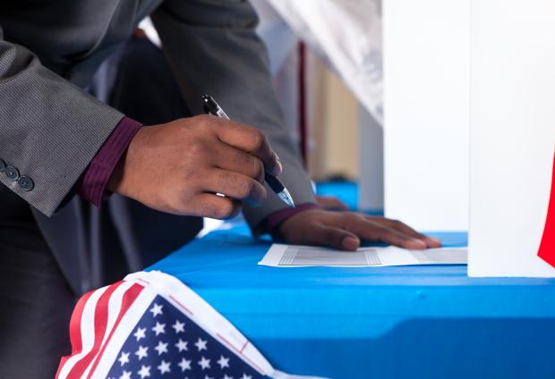 Hand of voter with a pen filling out a ballot