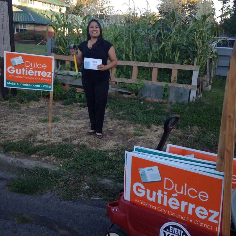 Dulce Gutierrez standing next to an election sign with a hammer in her hand